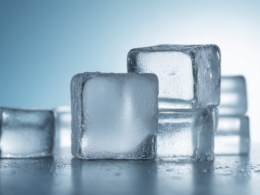 Large clear ice cubes with water droplets on a cool blue background