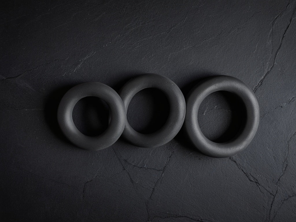 Three grip strengthener rings on a dark slate surface