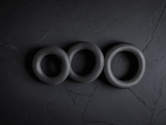 Three grip strengthener rings on a dark slate surface