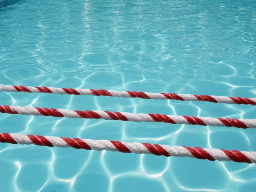 Clear swimming pool water with lane ropes in summer sunlight
