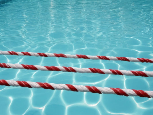 Clear swimming pool water with lane ropes in summer sunlight