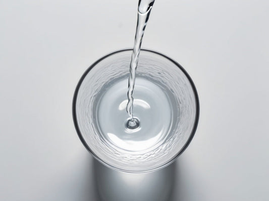 Clear fresh water pouring into a plain glass, top-down view