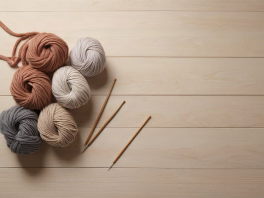 Yarn skeins and knitting needles arranged on a wooden table