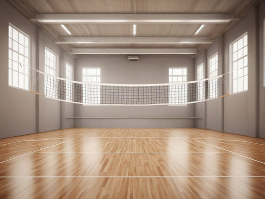 Empty indoor gym court with a volleyball net and polished wood floor
