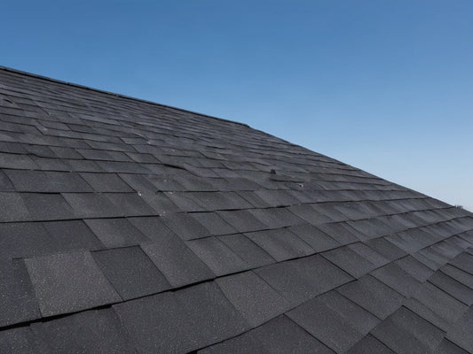 A residential rooftop covered in dark asphalt shingles under bright midday sun