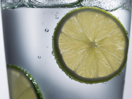Close-up of sparkling water with rising bubbles and a lime wheel in a clear glass