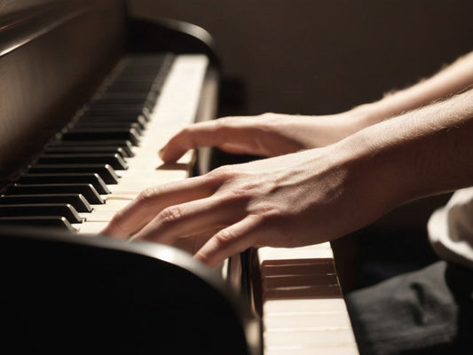 Close-up of hands resting on piano keys in warm practice room light