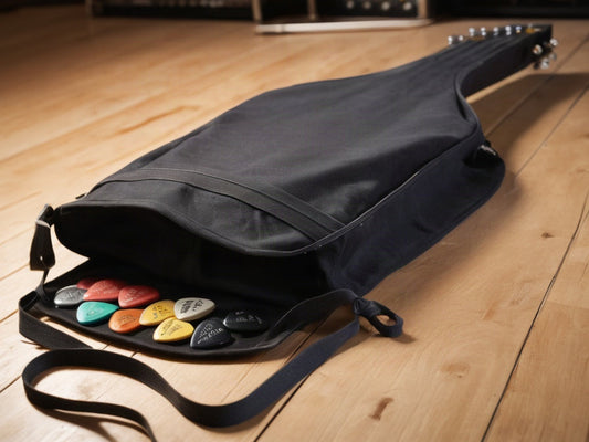 Open gig bag with cables and guitar picks on a wooden floor