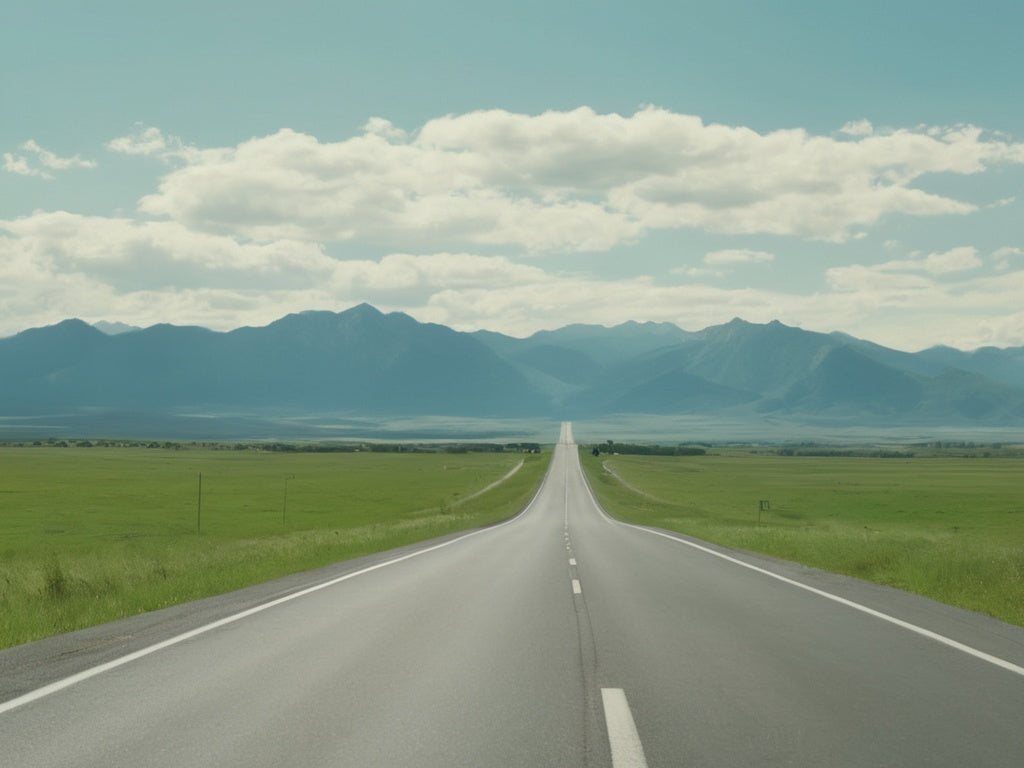 Open highway stretching toward distant mountains on a summer road trip