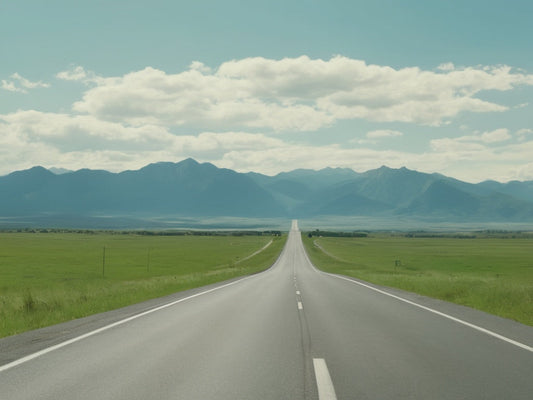 Open highway stretching toward distant mountains on a summer road trip