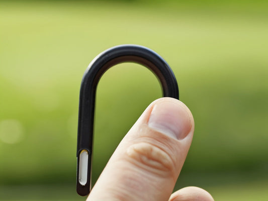 Finger hooked through a bottle carry-loop handle outdoors