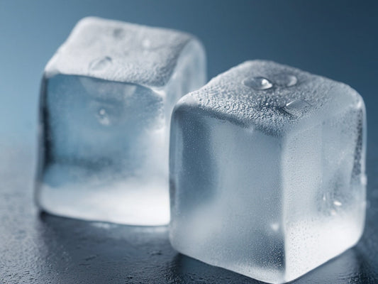 Macro close-up of large clear ice cubes with frost on a cool blue surface