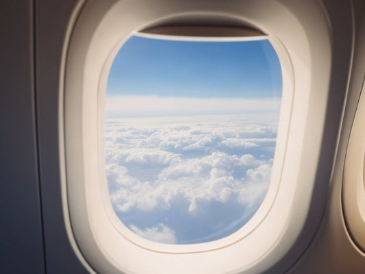 Airplane window with clouds and blue sky