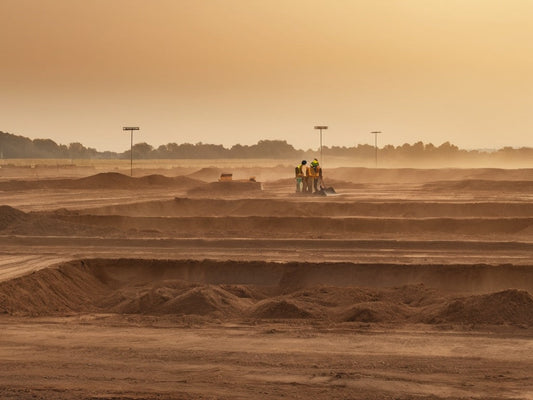 Construction site at sunrise with distant workers in heat haze
