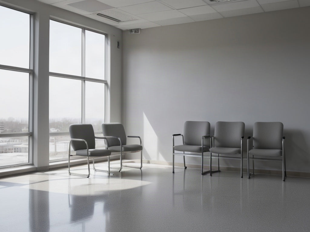 An empty waiting area with plain gray chairs beside a tall window in soft morning light