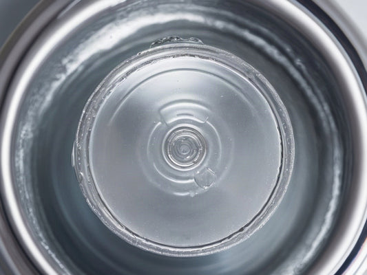 Top-down view into the mouth of a water bottle with droplets on the rim