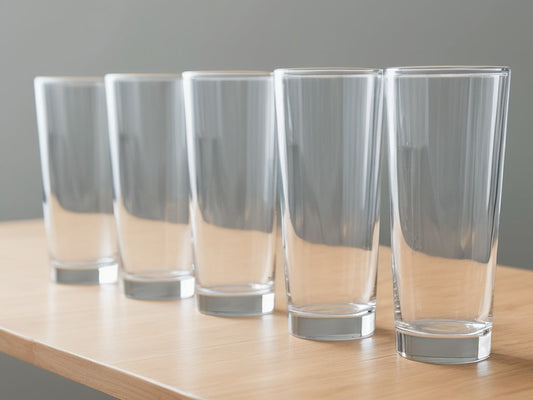 A row of identical clear drinking glasses of water on a wooden table in daylight, no text or logos visible