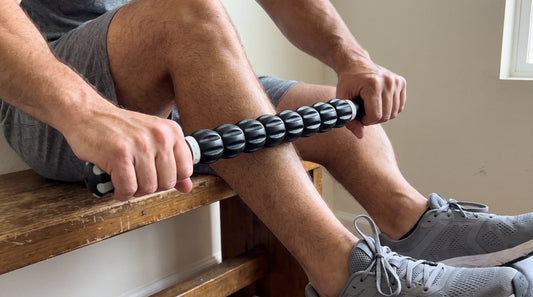 Man using the NuRich Muscle Roller stick on his calf while sitting on a bench