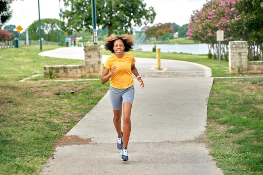 Woman running on a park path with a water bottle, active outdoor lifestyle